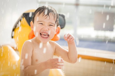 mixed-race boy having fun at the water park with large rubber duck in the background