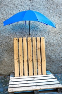 Seat made of old wooden pallets with blue umbrella