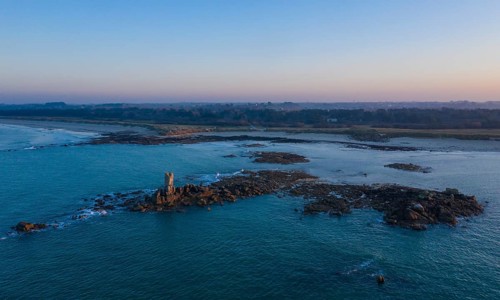 Aerial view of rock formations in the sea in front of the sandy beach Ker Emma and dunes Keremma shortly in front of sunset