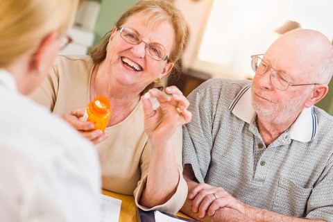 Doctor or nurse explaining prescription medicine to senior adult couple