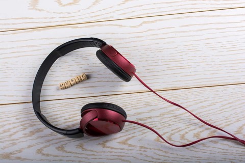 Dice-sized alphabet cubes spelling music and red headphones on wooden background