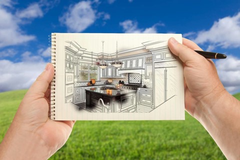 Male hands holding pen and pad of paper up with custom kitchen illustration outside near grass field and blue sky