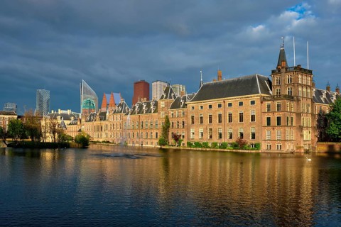 View of the Binnenhof House of Parliament and the Hofvijver lake with downtown skyscrapers in background. The Hague