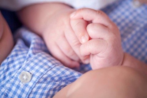 Close-up of infant hands while laying on lap of mother