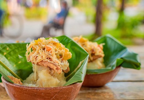 Vigoron with leaves served on a wooden table