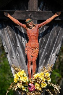 Geschnitztes Wegkreuz mit Blumenschmuck