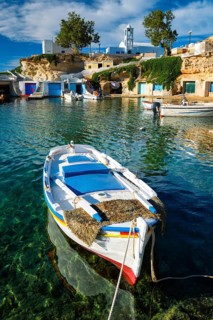 Fishing boat moored in crystal clear turquoise sea water in harbour in Greek fishing village of Mandrakia