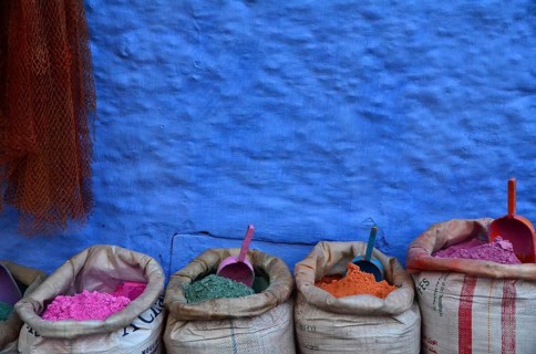 Colourful paint powder in bags in front of blue wall with shovel