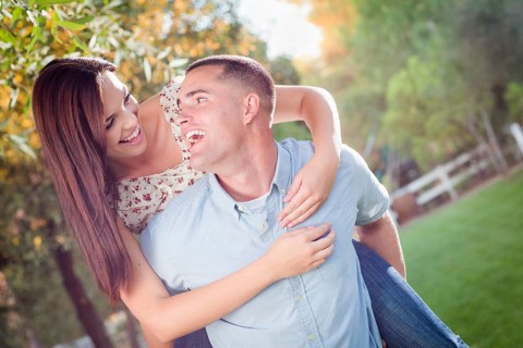 Happy romantic caucasian couple piggyback riding in the park