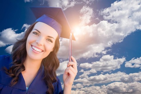 Happy graduating mixed-race woman in cap and gown