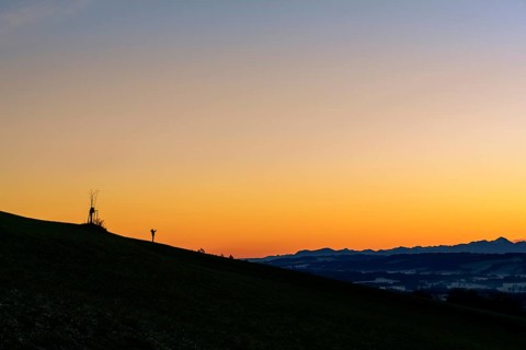 Handyfotograf bei Sonnenaufgang auf Bergruecken