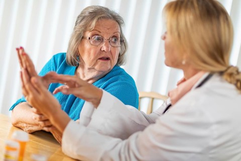 Female doctor talking with senior adult woman about hand therapy