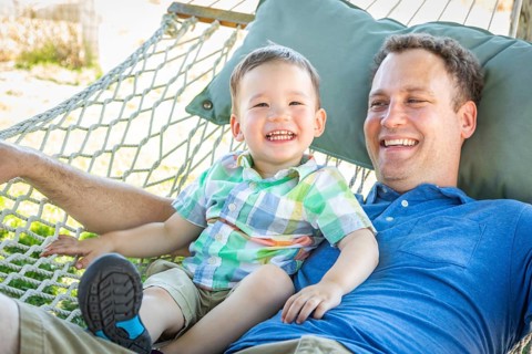 Caucasian father relaxing in hammock with mixed-race chinese son