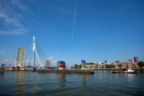 Tug boat towing barge with containers under open bascule part of Erasmusbrug bridge in Nieuwe Maas river. Rotterdam