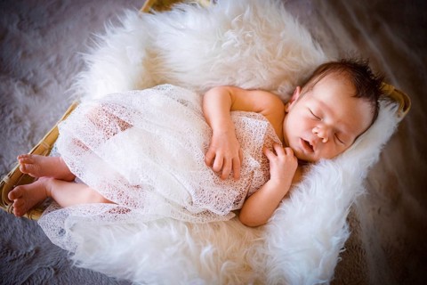Cute newborn baby boy sleeping in the basket on fluffy blanket
