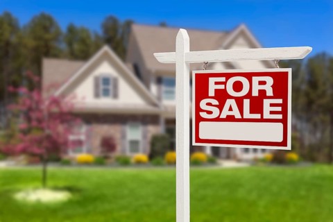 Home for sale real estate sign in front of beautiful new house