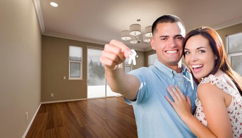 Young military couple with house keys in empty room of new home