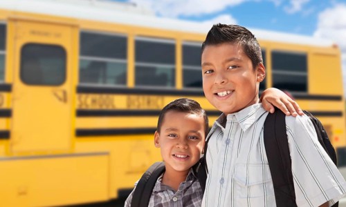 Young hispanic boys walking near school bus