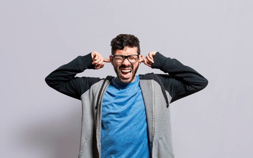Irritated person screaming covering his ears