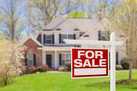 Home for sale real estate sign and beautiful new house