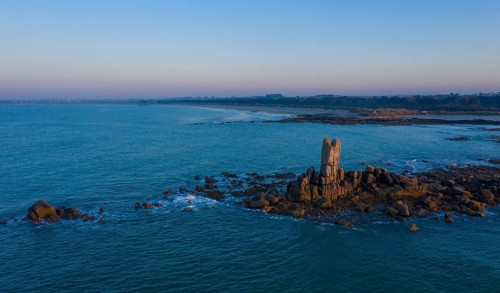 Aerial view of rock formations in the sea in front of the sandy beach Ker Emma