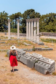 Young woman with dress in front of ruins with columns