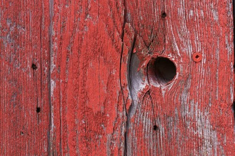 Wooden board with knothole painted in red