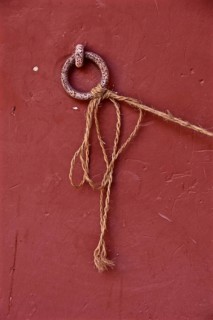 Metal ring on red wall with tied long cord