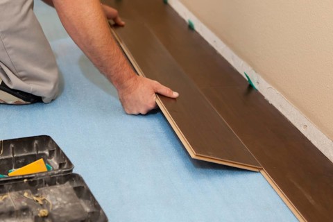 Man installing new laminate wood flooring abstract