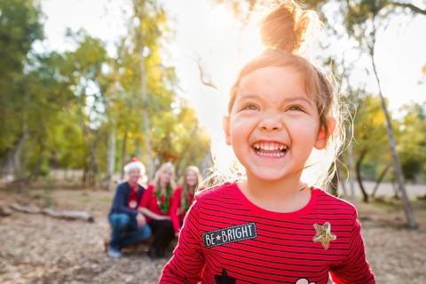 Cute mixed-race baby girl christmas portrait with family behind outdoors