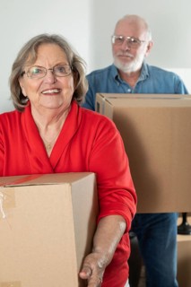 Senior adult couple carrying moving boxes