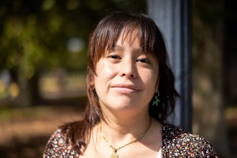 Portrait of a young Latin woman in a park leaning on a lamppost