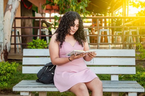A cute girl sitting on a bench reading a book