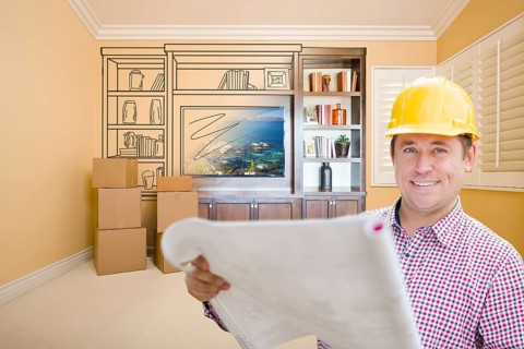 Male construction worker wearing hard hat in room with drawing of entertainment unit on wall