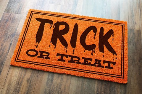 Trick or treat halloween orange welcome mat on wood floor background
