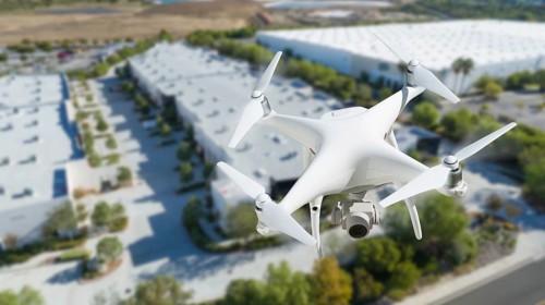 Unmanned aircraft system quadcopter drone in the air near corporate industrial building