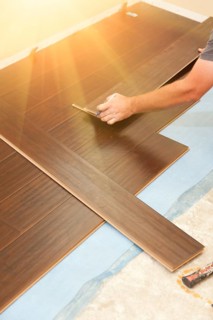 Man installing new laminate wood flooring abstract