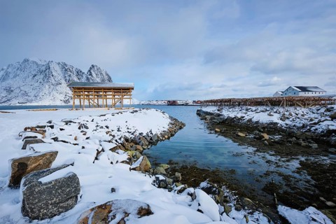 Drying flakes for stockfish cod fish in fjord in winter with snow