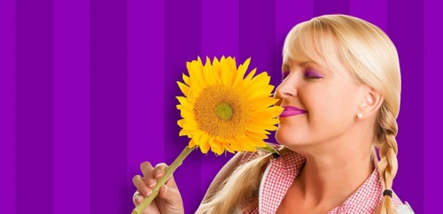 Beautiful girl holding yellow sunflower against purple striped background