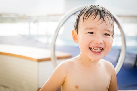 mixed-race boy having fun at the water park with large rubber duck in the background