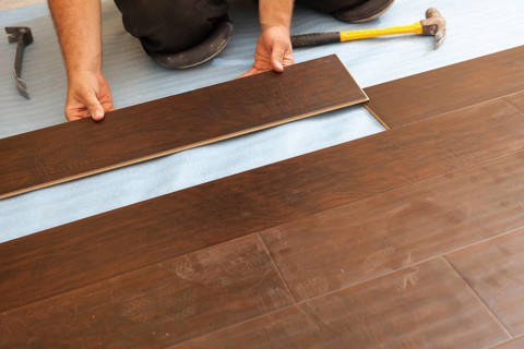 Man installing new laminate wood flooring abstract