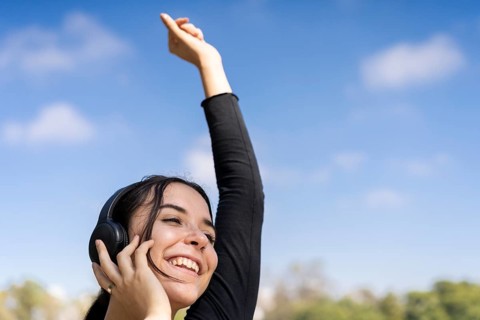 Young woman listening to music outdoors with headphones. Expression of happiness