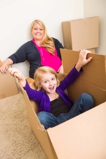 Playful young family in empty room playing with moving boxes