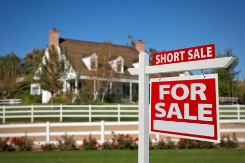 Short sale home for sale real estate sign in front of new house