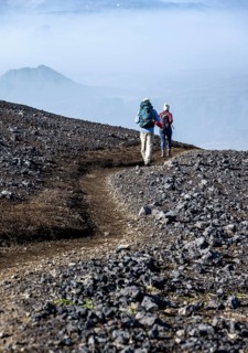 Two hikers on trail through volcanic landscape