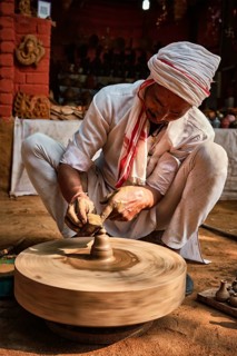 Indian potter at work: throwing the potter's wheel and shaping ceramic vessel and clay ware: pot