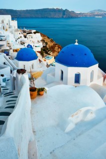 Famous view from viewpoint of Santorini Oia village with blue dome of whitewashed greek orthodox Christian church of traditional greek architecture