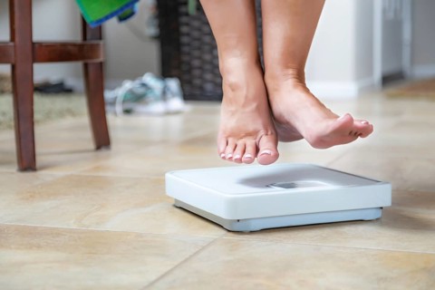 Woman floating slightly above surface of weight scale