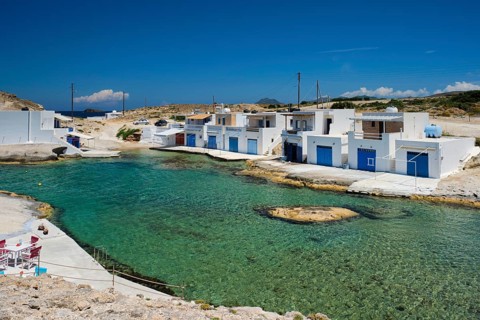 The beach of Agios Konstantinos with crystal clear turquoise water and traditional greek white houses. Milos island