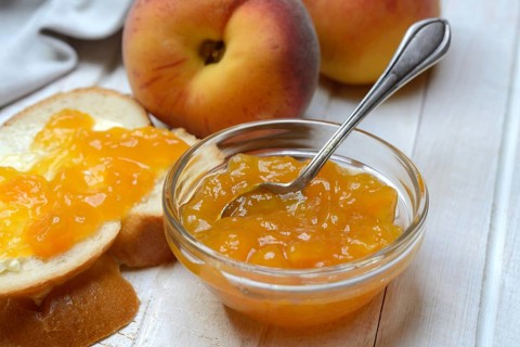 Peach jam in a glass bowl with spoon